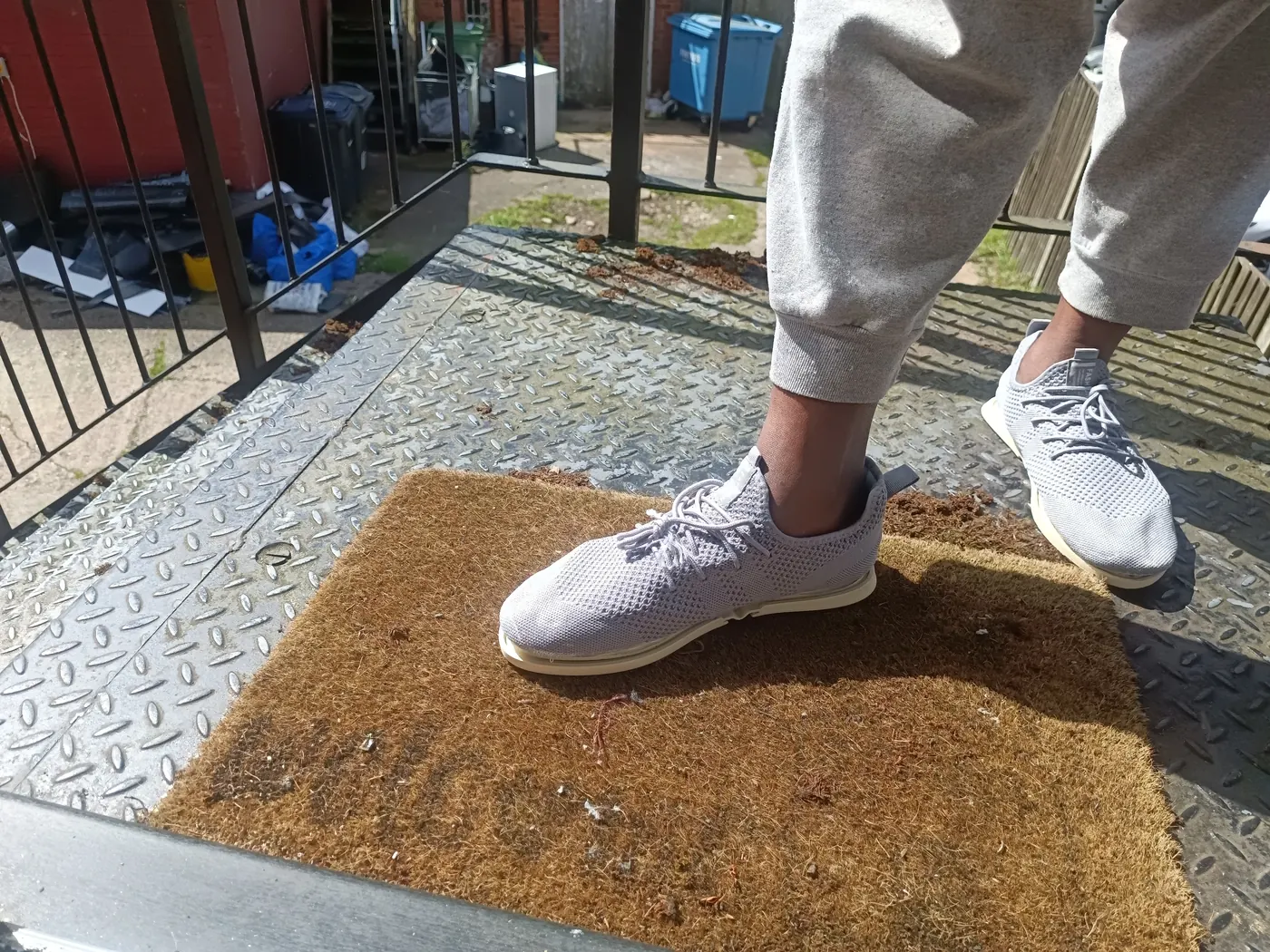 A foot presses the heel of the prototype on a coir doormat; the sole begins to release.